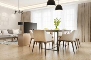 Open-concept living and dining area with a wooden dining table, beige chairs, tall windows with sheer curtains, and modern black pendant lights above the table.
